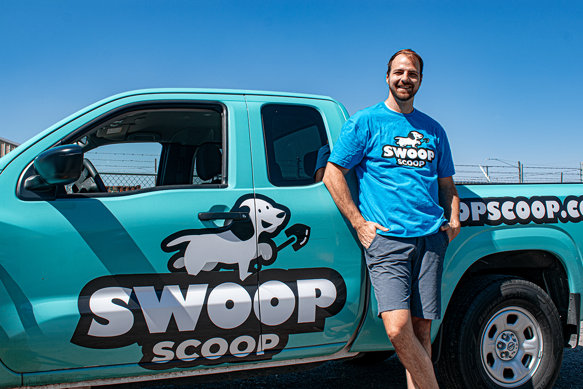Swoop Scoop's Office Manager andrew standing in front of a pooper scooper truck branded in Swoop Scoop Colors.